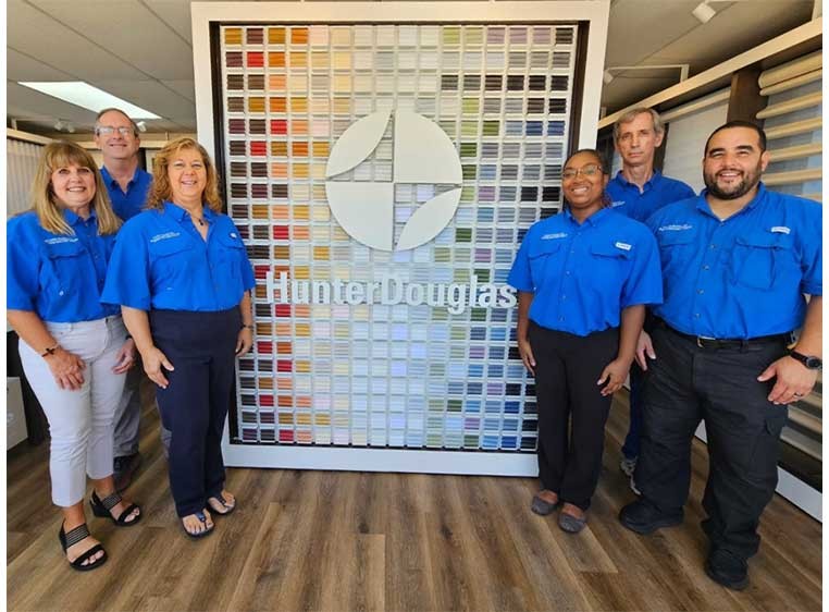 Company staff posing for a photo in the showroom by a Hunter Douglas display